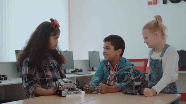 Blandad ras grupp kreativa barn som arbetar med det tekniska projektet i skolan. Elev pojke och flickor leka och lära sig att styra roboten i klassen. — Stockvideo