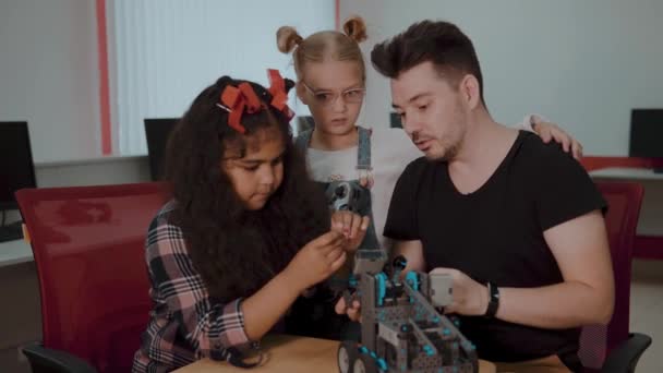 Karışık ırk grup okul çocuklar uzaktan kumanda ile robotik makine kontrol birlikte öğretmen. Okulda teknoloji projesi üzerinde çalışan yaratıcı çocuklar. — Stok video