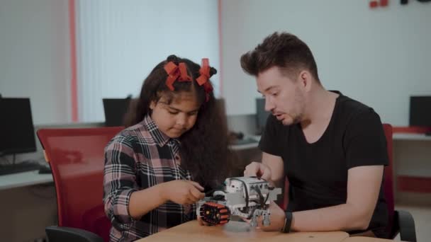 Grupo Racial Misto de crianças em idade escolar controlando máquina robótica com controle remoto juntos professor. Crianças criativas trabalhando no projeto de tecnologia na escola . — Vídeo de Stock