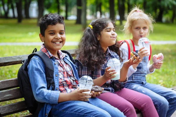 Grupo Racial Misto de crianças da escola almoçando juntas na pausa ao ar livre perto da escola. Voltar ao conceito de escola . — Fotografia de Stock