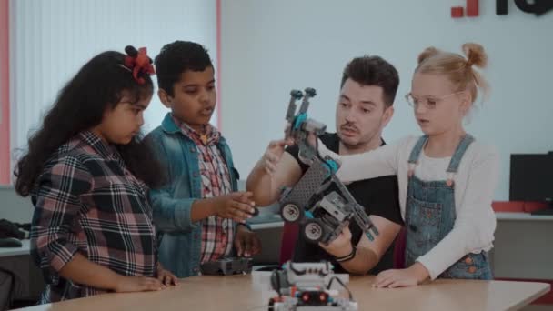 Karışık ırk grup okul çocuklar uzaktan kumanda ile robotik makine kontrol birlikte öğretmen. Okulda teknoloji projesi üzerinde çalışan yaratıcı çocuklar. — Stok video