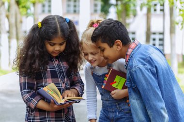 Okula dönüyoruz. Backpacks Ile üç arkadaş yakın yukarı sarılmaya ve okulun önünde gülüyor. Okul çocuklar karışık ırk grup okulda eğlenmek.