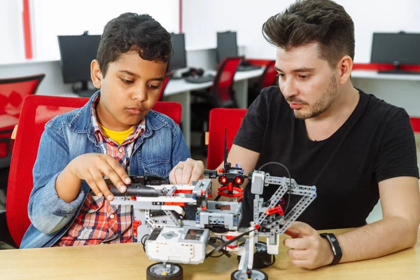 Mixed Racial group of School children controlling robotic machine with remote control together teacher. Creative kids working on the tech project at school.