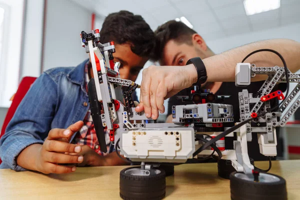 Mixed Racial group of School children controlling robotic machine with remote control together teacher. Creative kids working on the tech project at school. — Stock Photo, Image