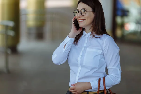オフィス近くの携帯電話を呼び出す流行の服でスタイリッシュな笑顔ビジネス女性の肖像画. — ストック写真