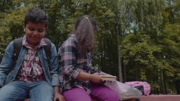 Terug naar school. Drie vrienden met rugzakken huging en lachen in de buurt van school. Gemengde rassengroep school kinderen plezier in het Park. Slow Motion-opname. — Stockvideo