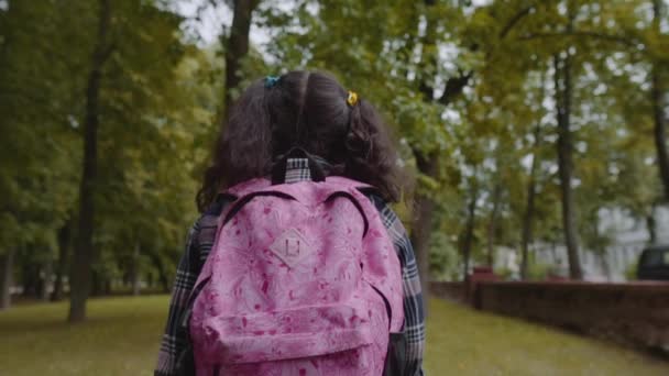 Vue arrière de l'écolière avec sac à dos marchant dans le parc. Retour à l'école. Prise de vue au ralenti . — Video