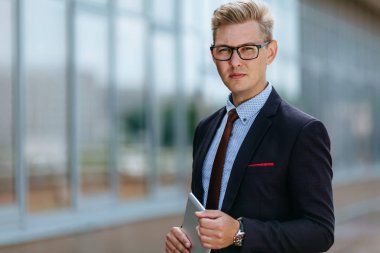 Dijital tablet ile mutlu işadamı. Ofis binasının arka planında elinde tablet Pc ile trendy giysiler içinde bir Erkek yönetici portresi. Modern teknoloji kavramı