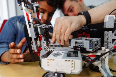 Karışık ırk grup okul çocuklar uzaktan kumanda ile robotik makine kontrol birlikte öğretmen. Okulda teknoloji projesi üzerinde çalışan yaratıcı çocuklar.