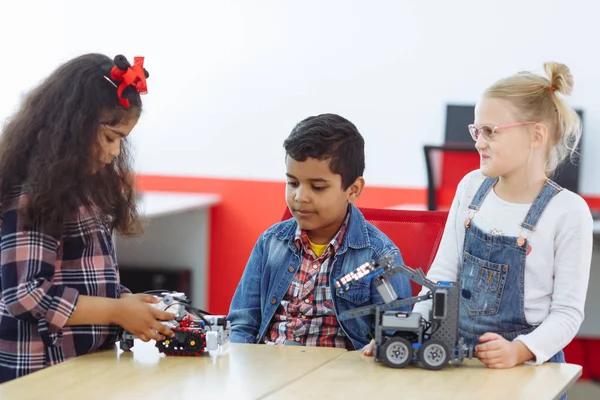 Mixed Racial group of Creative kids working on the tech project at school. Student boy and girls play and learn to control the robot in the class.