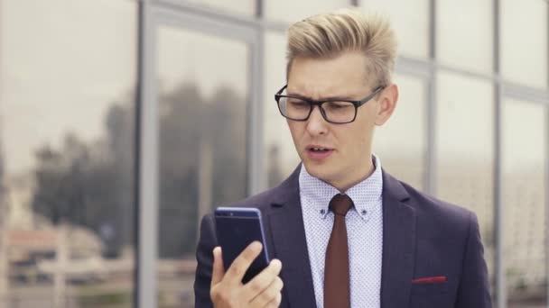 Empresário descontente ter desagradável vídeo chat online. Homem a expressar a sua irritação. Homem irritado usando Smartphone . — Vídeo de Stock