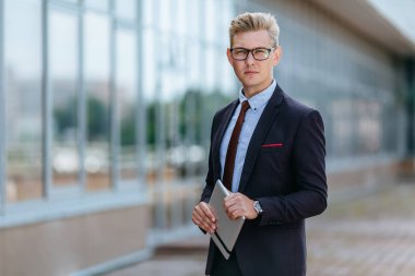 Dijital tablet ile mutlu işadamı. Ofis binasının arka planında elinde tablet Pc ile trendy giysiler içinde bir Erkek yönetici portresi. Modern teknoloji kavramı