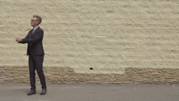 Handsome and Happy Businessman Energetically Dancing on a Street in front of Urban Concrete Wall. Smiling man Wearing a Dark Suit. — Stock Video