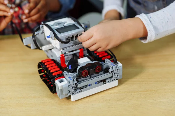 Blandad ras grupp skolbarn sitter i klass med DIY Robot, Stem utbildning Concept. Royaltyfria Stockbilder