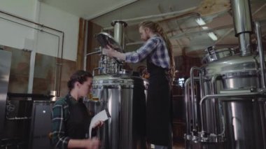 Bira fabrikasında ya da bira fabrikasında çalışan panolu kadınlar. Bira fabrikası işçisi bir zanaat bira fabrikasında bira fıçısının kapağını açıyor. Küçük işletme konsepti.