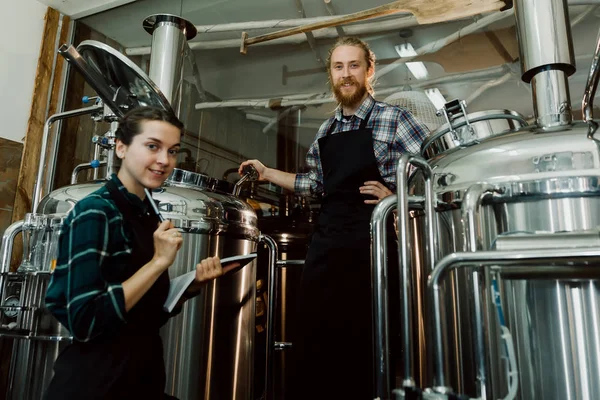 在啤酒厂或啤酒厂工作剪贴板的妇女。啤酒厂工人在精酿啤酒厂打开啤酒桶盖。小型企业概念. — 图库照片
