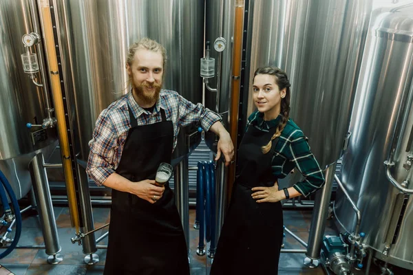 Trabajadores cerveceros mirando cerveza recién hecha en tubo de vidrio y discutiéndolo. Cervecera macho y hembra probando cerveza en la fábrica de cerveza. 4k. Concepto de pequeña empresa . —  Fotos de Stock