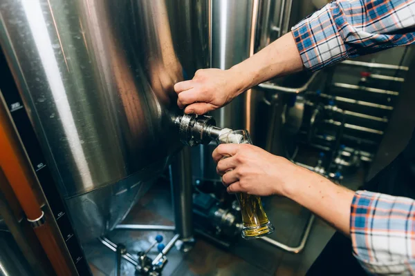 Birraio che riempie la birra in vetro da serbatoio a birreria. Concetto di impresa familiare . — Foto Stock