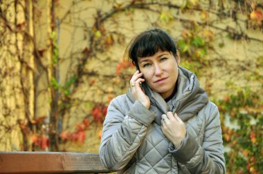 Sonbahar şehrin arka plan telefonda konuşurken güzel genç kız