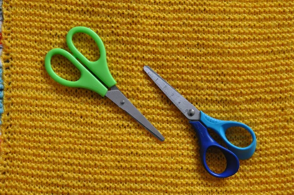 Pair of bright shiny silver steel fabric shears or designer scissors for cutting material lying on a grey textile — Stock Photo, Image