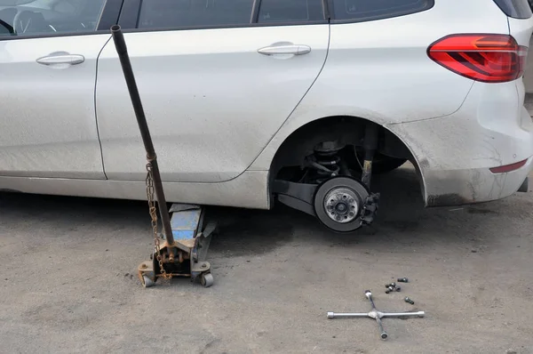 Substituindo rodas em um carro, jack mantém o corpo em posição levantada — Fotografia de Stock