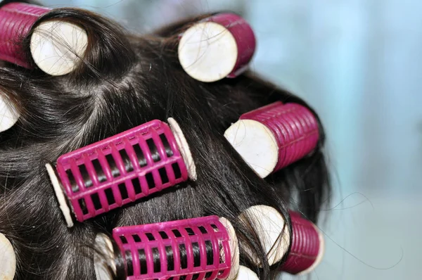 hair curlers in the dark hair of a young woman.