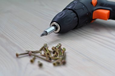 Ahşap bir masa üzerinde elektrikli tornavida ve vidalar.