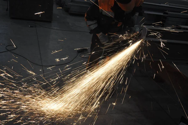Arbeiter in der Fabrik schneidet Metall. Funken fliegen — Stockfoto