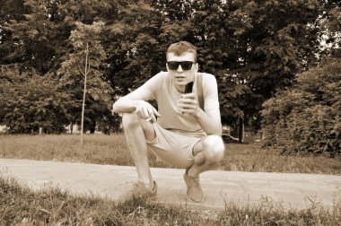 yarı sigara içen ve elinde akıllı telefon tutar