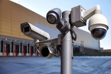 closed circuit camera Multi-angle CCTV system on the background of the warehouse buildings. clipart