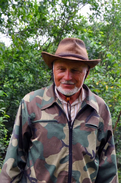 Viajero de mediana edad. Retrato de un hombre adulto guapo con una barba gris y sombrero en ropa de camuflaje . —  Fotos de Stock