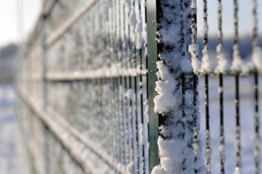 Arka planda metal bir çit üzerinde kar yapıştırma.