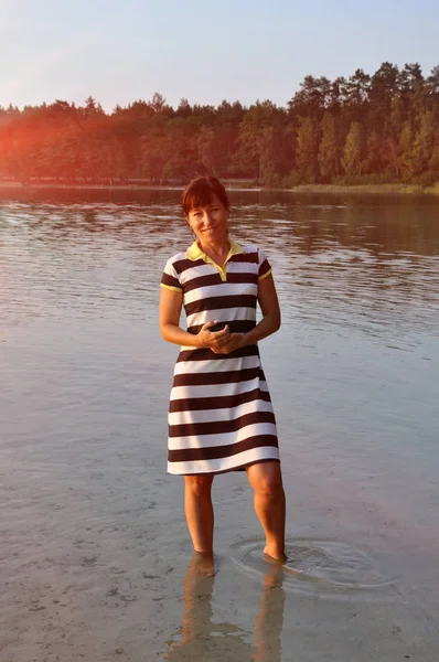 Güzel genç bir kadın. Açık havada. Göl suyunda durmak