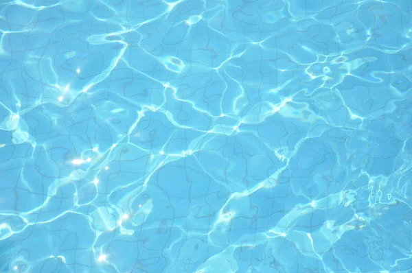 Plavecký bazén na dně zvlní a teče vlnami. Letní zázemí. Struktura vodní hladiny. — Stock fotografie