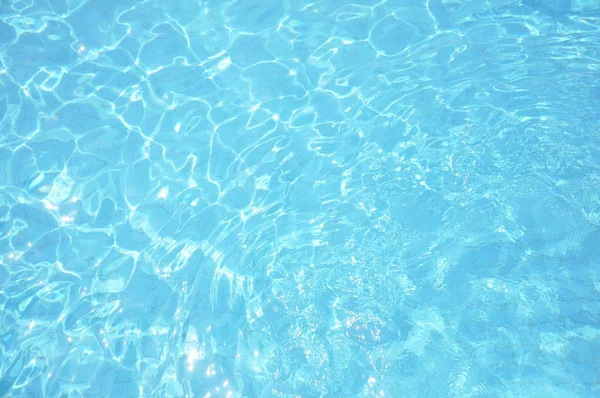 Los cáusticos del fondo de la piscina ondulan y fluyen con el fondo de las olas. Fondo de verano. Textura de la superficie del agua . — Foto de Stock