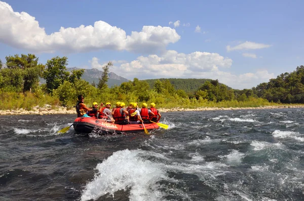 Rafting, un grup de tineri cu un ghid de rafting de-a lungul unui râu de munte. Sportul extrem și distractiv la o atracție turistică . — Fotografie, imagine de stoc