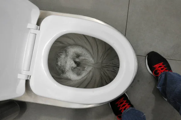 Empurre na sanita. Um homem flushes na casa de banho . — Fotografia de Stock