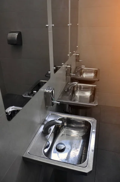 Moderner Innenraum einer öffentlichen Toilette. Waschbecken aus Edelstahl. — Stockfoto