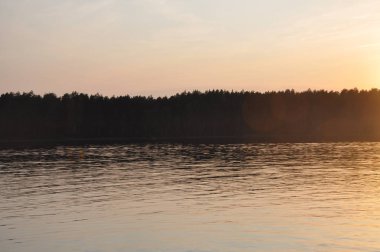 Batan güneşin ışınlarında bir orman gölünün berrak suları.