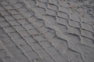 Toprak yüzeyde bir kamyonun lastik izleri var..