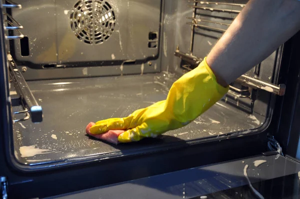 La limpieza del horno en la cocina. mano en un guante económico amarillo . —  Fotos de Stock