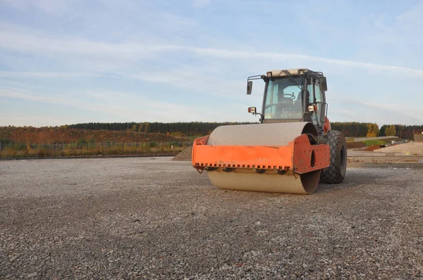 Orange road roller at the road construction. Construction machinery.