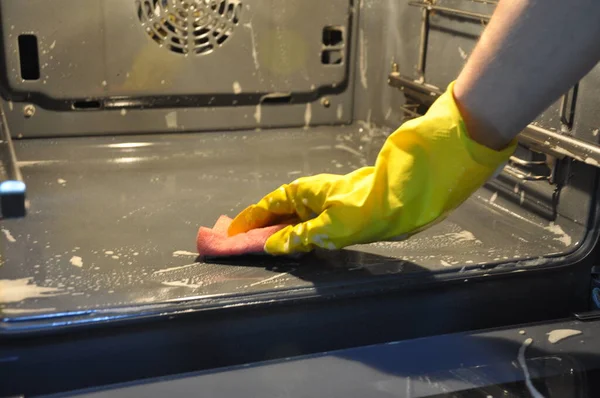 cleaning the oven in the kitchen. hand in a yellow economic glove.