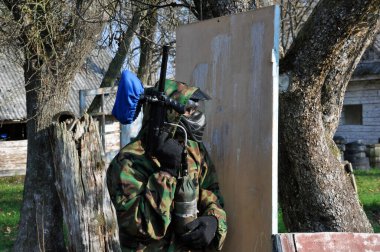 Aktif paintball oyunu. Koruyucu üniformalı ve maske takan bir paintball oyuncusu.