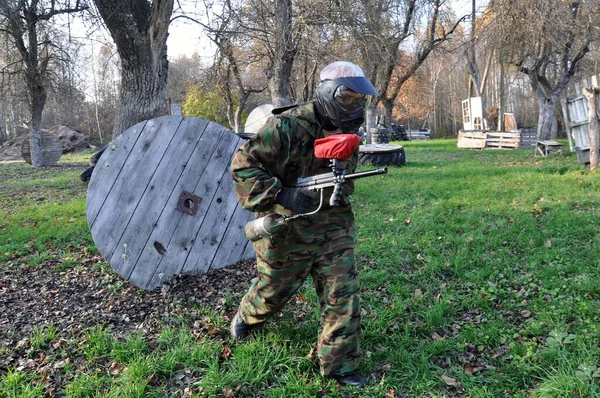 Juego activo de paintball. Paintball jugador en uniforme protector y máscara de primer plano . — Foto de Stock