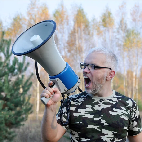Porträt eines jungen Mannes, der im Wald mit einem Megafon schreit. Konzept zur Suche nach Vermissten — Stockfoto