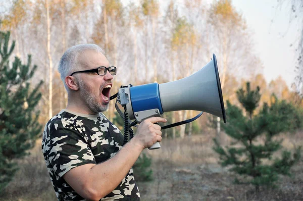 Portret młodego mężczyzny krzyczącego z megafonem w lesie. Koncepcja wyszukiwania zaginionych ludzi — Zdjęcie stockowe