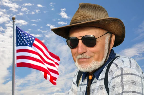 一位美国牛仔正站在蓝天上 上面挂着一面发展中的美国国旗 他戴着一顶草帽和一副黑眼镜 美国航天局提供的这一图像的要素 — 图库照片
