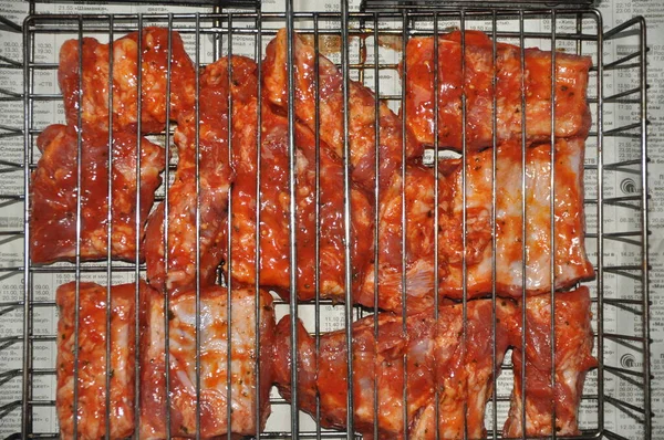 Slices of minced meat stew in a wire rack for cooking barbecue on a newspaper.