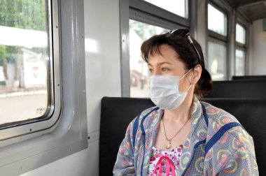 Tıbbi koruyucu maskeli bir kadın toplu taşıma araçlarına biniyor. Coronavirüs, COVID-19 gibi solunum enfeksiyonlarına karşı koruma kavramı